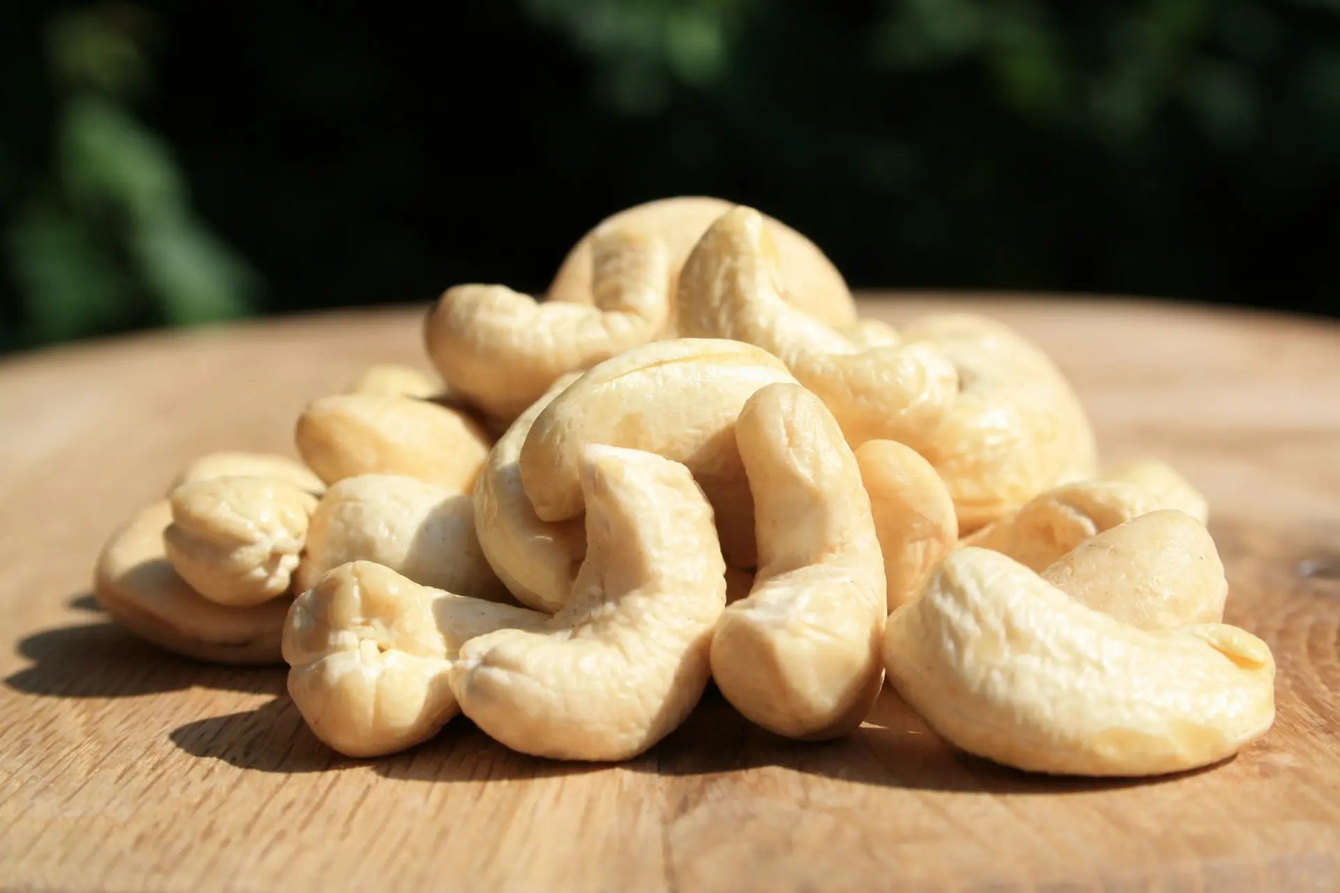 A pile of cashews sitting on top of a wooden table